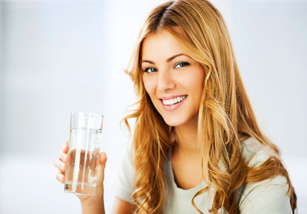 Young woman holding glass with Purified Water.